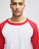 A raglan baseball T-shirt featuring a white body and red sleeves, worn by a model. The shirt has a logo.