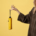 A yellow compact umbrella held by a person, with a plain background and a visible logo on the umbrella.