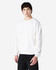 A white crewneck sweatshirt worn by a model, featuring long sleeves and a relaxed fit. It has a logo on it.