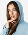 A blue hooded sweatshirt with a front pocket, worn by a young woman with long hair. It features a logo on the garment.