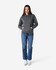 A grey Gildan Heavy Blend adult hooded sweatshirt worn by a model, paired with blue jeans and white shoes.