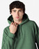 A green hooded sweatshirt with a large hood, featuring a logo, worn by a male model.