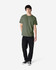 A green Gildan Heavy Cotton Adult T-Shirt, worn by a model paired with black jeans and sneakers, standing against a white background.