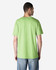 A man wearing a bright green Gildan Heavy Cotton Adult T-Shirt, viewed from the back. The shirt has a logo on it.