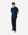 A man stands wearing a navy blue Gildan Softstyle adult double pique polo and black jeans. The polo features a logo.