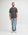 A midweight adult t-shirt in olive green, paired with black jeans and sneakers. The model is walking.