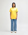 A midweight adult t-shirt in bright yellow, paired with black pants and black sneakers, featuring a logo.