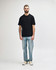 A black midweight t-shirt displayed on a model, paired with black jeans and sneakers. Features a logo.