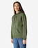 A green Gildan Softstyle adult hooded sweatshirt worn by a model, featuring a front pocket and a drawstring hood.