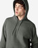 A soft grey hooded sweatshirt, featuring a front pocket and a hood, worn by a model. It has a small logo.