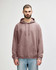 A hooded sweatshirt in a mauve colour, featuring a front pocket and drawstrings, worn by a model.