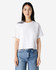 A white boxy T-shirt featuring short sleeves, paired with blue jeans, and has a logo on it.