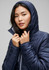A woman in a navy unisex patrol jacket with a hood, adjusting the collar, featuring a sleek design.