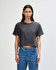 A women's boxy t-shirt in dark grey, featuring a round neckline and short sleeves, styled with high-waisted jeans.