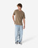 A unisex heavyweight cotton T-shirt in earthy brown, worn with light blue jeans and dark sneakers.