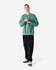 A unisex crewneck sweatshirt in green, paired with black cargo pants, featuring a logo on the front.