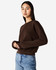 A brown women's crewneck sweatshirt with long sleeves, featuring a fitted hemline. The model is wearing denim jeans.