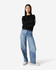 A black crewneck sweatshirt paired with light blue wide-leg jeans on a model. The sweatshirt has a logo.