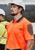 A man wearing an orange hi-vis short sleeve polo shirt with a pocket and a logo, paired with a safety helmet.