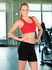 A model wearing black women's dress shorts and a red crop top poses in a gym setting.