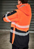A unisex softshell jacket featuring bright orange and black colours, with reflective stripes and a hood.