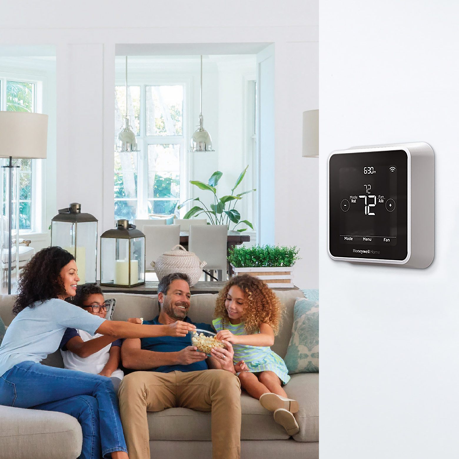 family sitting on couch with thermostat in foreground