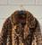 A bold leopard print faux fur maxi coat from designer Dennis Basso. Luxurious texture and eye-catching pattern make this a true statement outerwear piece. Perfect for elevating any winter outfit with a touch of glamour and animal-print edge.
