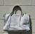 Soft, buttery leather meets a structured silhouette with polished gold-tone hardware and a clean, crisp white finish. Featuring dual rolled handles plus a detachable, adjustable crossbody strap, this satchel transitions effortlessly from work to weekend. Roomy interior with slip and zip pockets keeps essentials organized on the go.