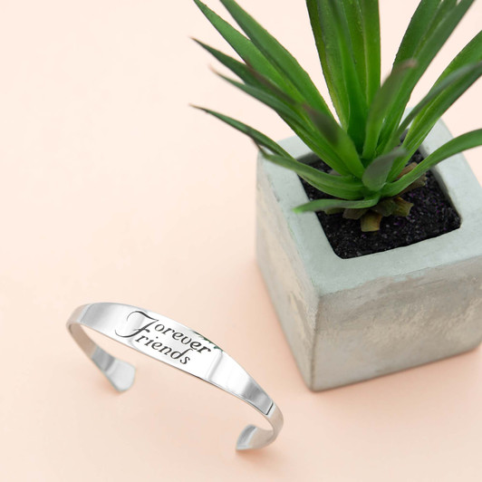 Inspirational stainless steel cuff bracelet with engraved words 'Forever Friends' on the outside. Adjustable and hypoallergenic, perfect as a thoughtful gift for friends.