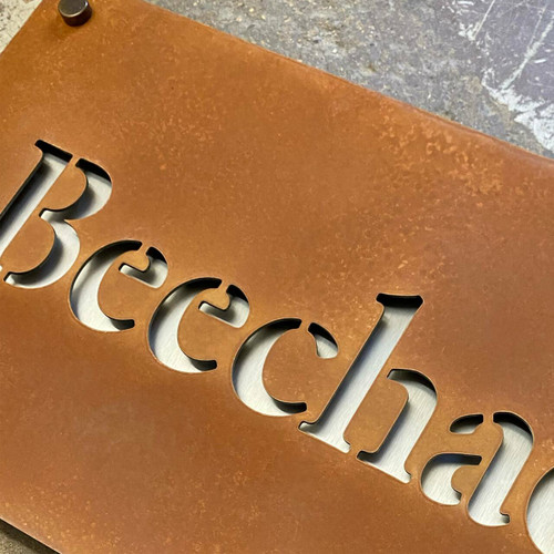 Double layer sign with a Corten steel front layer and stainless steel back layer