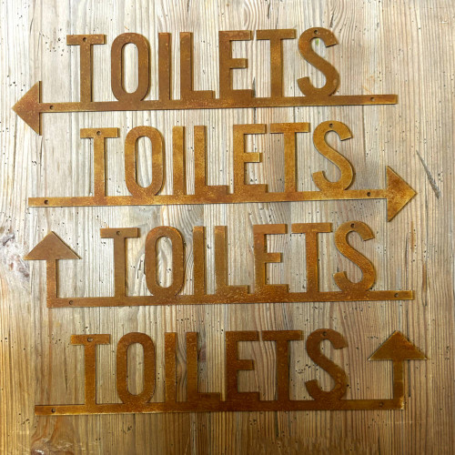 Rusty steel toilet sign with directional arrow.