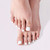 Feet with white press-on toenails showing a clean, natural-looking pedicure