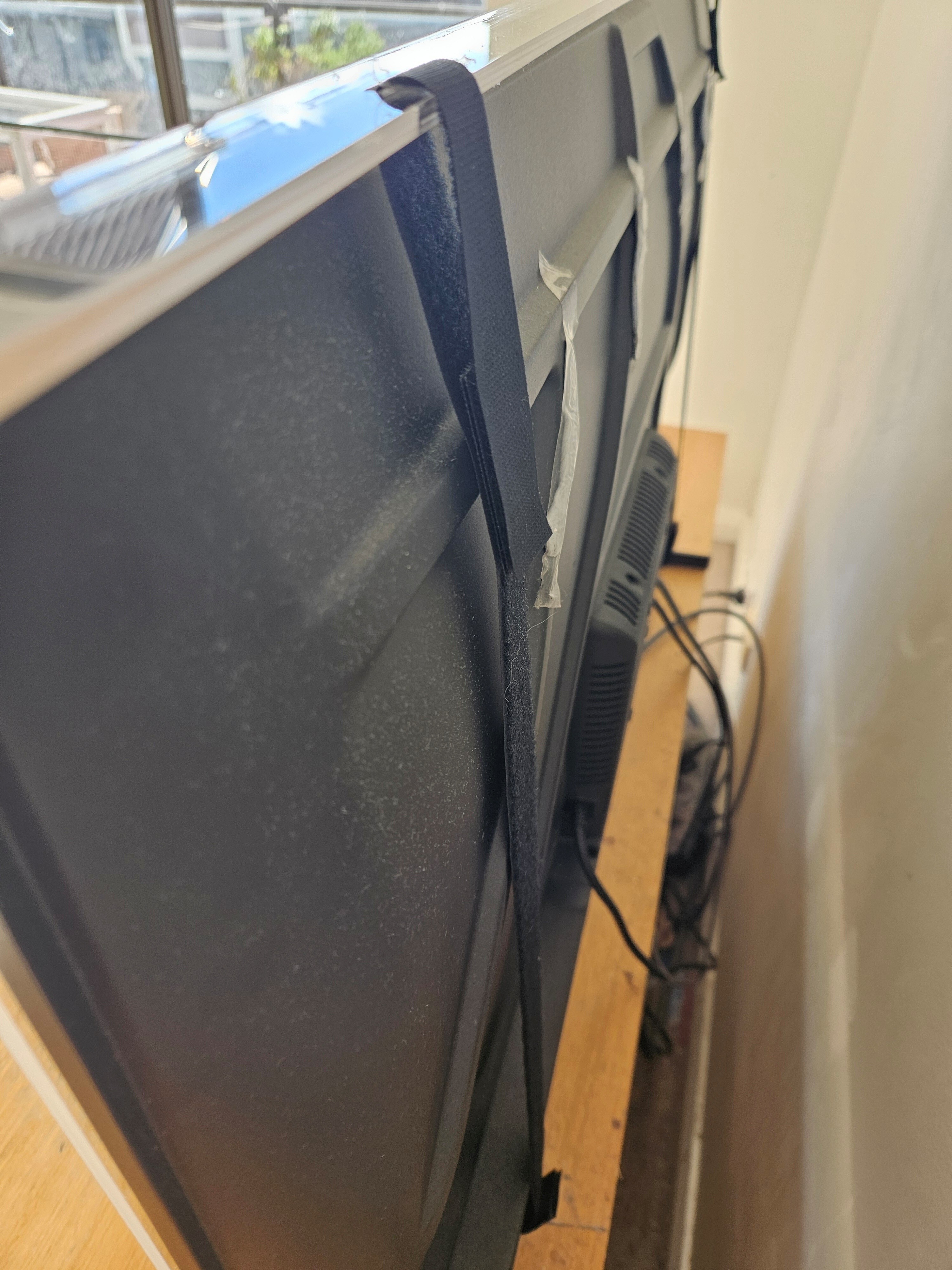 Velcro straps securing the screen protector to the rear of the TV
