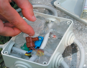 Gemini Gel being pressed into an outdoor electrical junction box encapsulating cable connectors