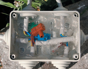 Completed Gemini Gel waterproof seal inside an outdoor electrical junction box showing transparent gel encapsulating connections
