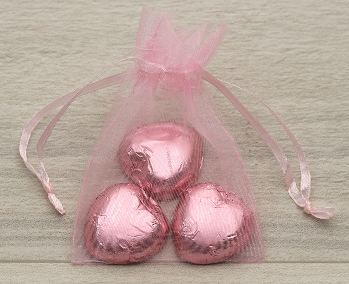 Baby pink organza bags containing three foil wrapped chocolate