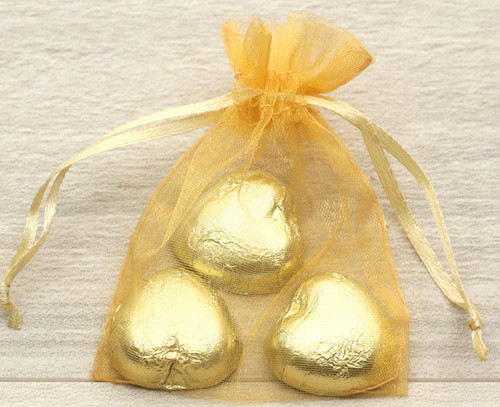 Gold organza bags containing three foil wrapped chocolate hearts