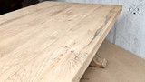The Charlested Oak Dining Table against a soft, blurred background, focusing on the table's strong presence