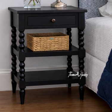 An angled detailed view of the Montclair Side Table in Black showcasing its bobbin leg detailing and functional drawer and display shelving.
