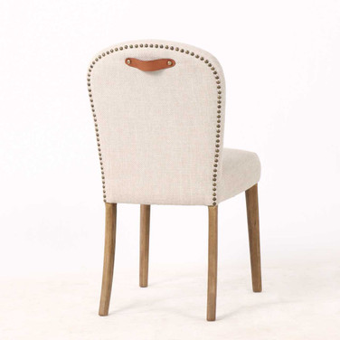 Three quarter rear view of the Stratford Dining Chair in high-performance fabric upholstery with natural legs and top grain leather pull handle, showcasing clean contemporary design details and classic studded trim by Thomas & Hurley.