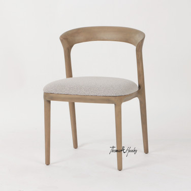 The Laguna Dining Chair by Thomas and Hurley with curved timber backrest and textured upholstered seat for contemporary luxury dining interiors.