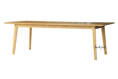 Angled front view of the Lofthouse dining table in natural oak by Thomas & Hurley highlighting elegant tapered legs and contemporary dining table design.