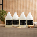 Amenie Sicilian Tangerine full product line of gallon bottles displayed on a wooden surface in a natural setting