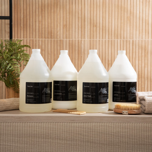 Amenie Sicilian Tangerine full product line of gallon bottles displayed on a wooden surface in a natural setting