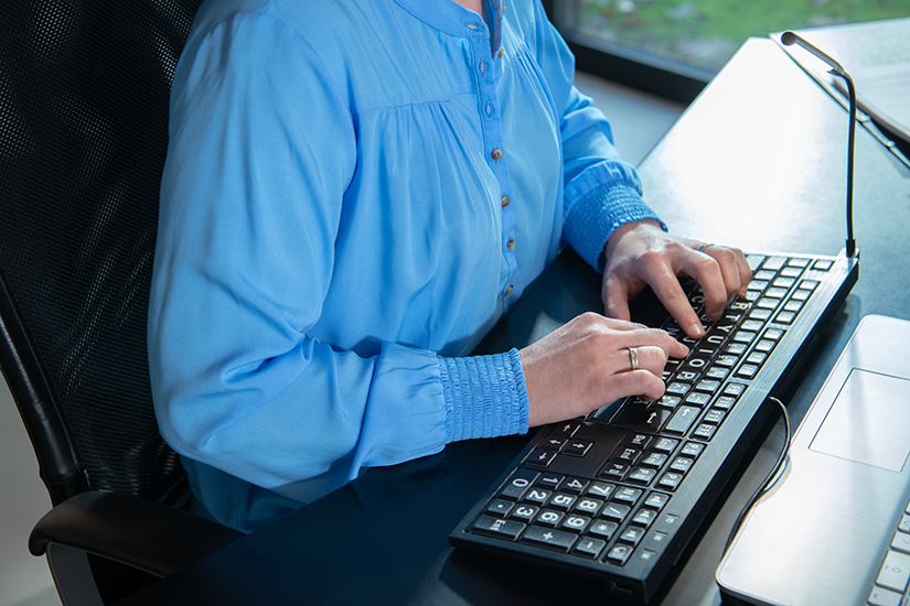 Een vrouw gebruikt eentoetsenbord voor slechtzienden
