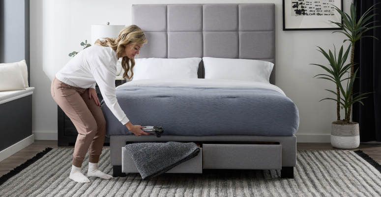 Person putting sheets inside of bed frame drawer