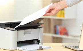 Person feeding paper into an HP printer showcasing the standard printing technology.