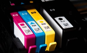 HP toner cartridges in cyan, magenta, yellow, and black ready for multi-color printing.