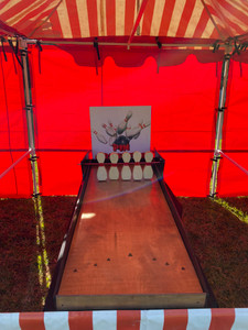 "A miniature table top bowling game set up on a flat surface. The game features small bowling pins arranged in a triangular formation at one end, with a tiny bowling ball nearby. Players roll the ball down the small lane to knock over the pins, creating a fun, compact version of traditional bowling." "A miniature table top bowling game set up on a flat surface. The game features small bowling pins arranged in a triangular formation at one end, with a tiny bowling ball nearby. Players roll the ball down the small lane to knock over the pins, creating a fun, compact version of traditional bowling."