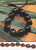 Black Kukui Nut Bracelet on top of a wooden table with decorative flora beneath.